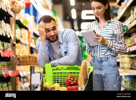 Una Joven Pareja Divertida Con Una Lista De Compras En El Supermercado