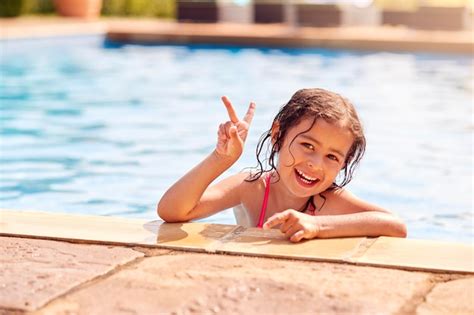 Premium Photo Portrait Of Young Girl Leaning On Edge Of Swimming Pool