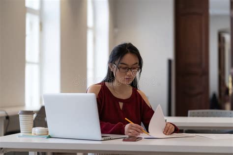 Focused Asian Female Student Preparing For Exam Or Doing Homework In