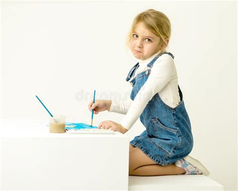 Cute Blonde Girl Sitting On Her Knees And Painting With Brush Stock