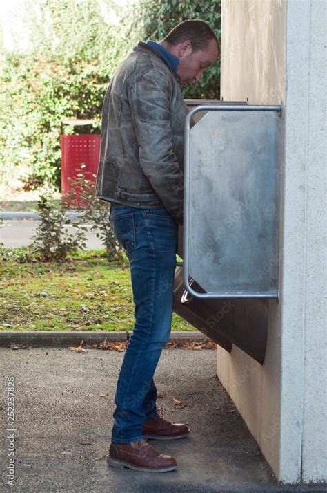 Portrait Of Man Peeing In Metallic Public Toilets For Men In Urban Park
