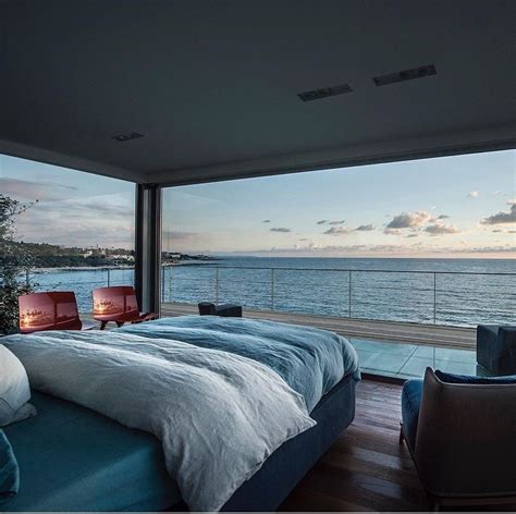 a large bed sitting in the middle of a bedroom next to a window overlooking the ocean