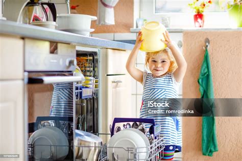 Little Adorable Cute Toddler Girl Helping To Unload Dishwasher Funny