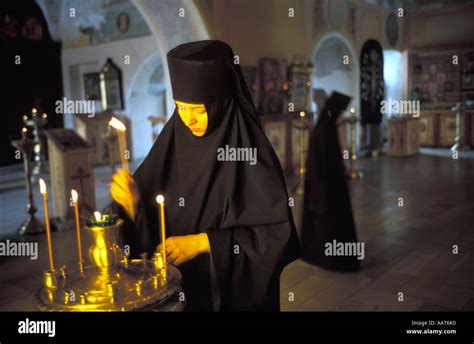 Nun Lighting A Candle Inside The Assumption Cathedral Of The Holy