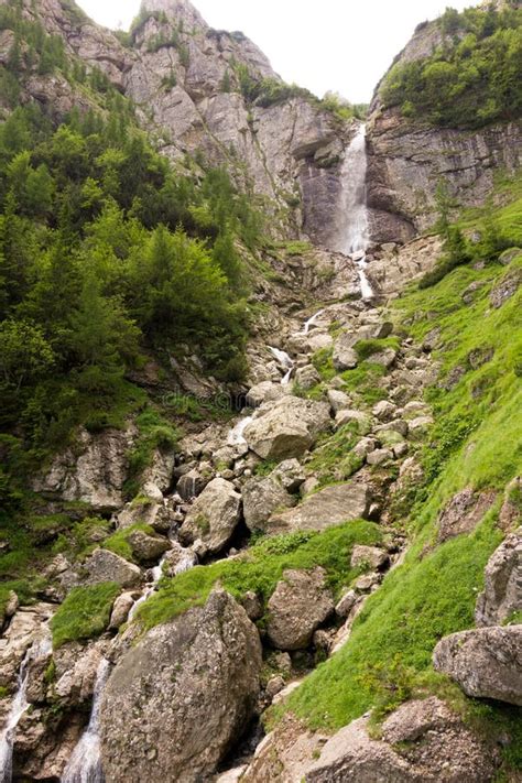 Beautiful Waterfall On A Rocky Valley With Scattered Vegetation Stock