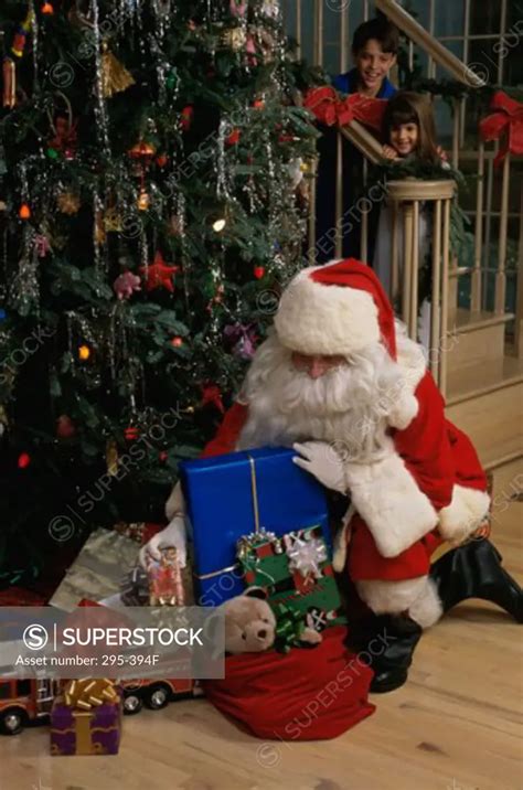 Santa Claus Putting Christmas Presents Under A Christmas Tree Superstock