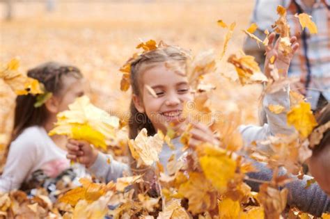 Children Are Lying And Playing On Fallen Leaves In Autumn City Park