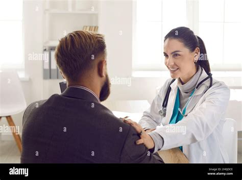 Friendly Female Doctor Touches Shoulder Of Male Patient For
