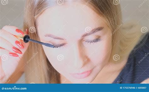 Pretty Blond Woman Applying Mascara Make Up On Her Eyelashes In Front