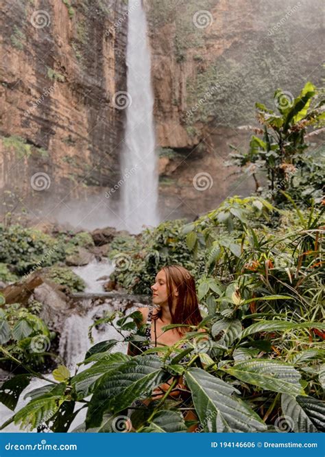 Young Woman Traveller At The Waterfall Surrounded By The Jungles Red