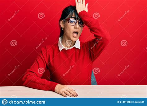 Young Brunette Woman With Bangs Wearing Glasses Sitting On The Table