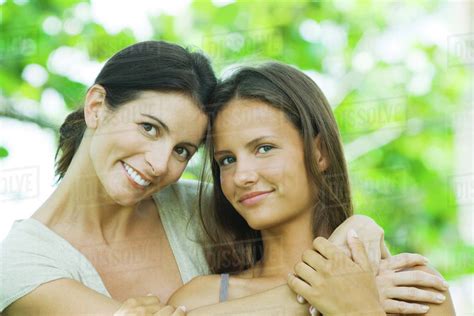 Mother Embracing Teen Daughter Both Smiling At Camera Portrait