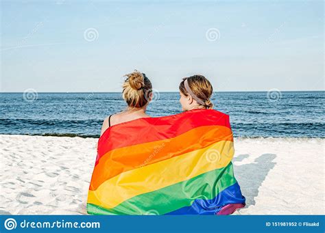 lesbian couple in love on the beach with a rainbow flag symbol of the