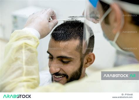 رجل سعودي خليجي في زيارة لصالون الحلاقة ، يقوم الحلاق بالعناية و الاهتمام بشعرالزبون وجعله انيقو