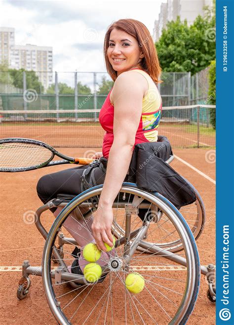 Disabled Young Woman On Wheelchair Playing Tennis On Tennis Court