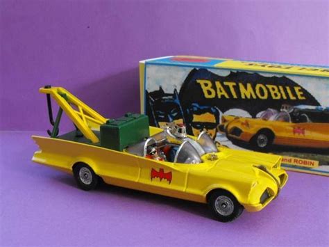 A Yellow Toy Car With Batmans Batmobile In The Back