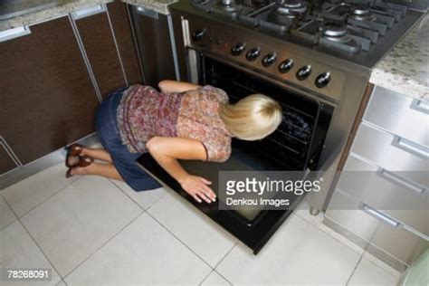A Woman Kneeling Down To Look At An Oven Stock Foto Getty Images
