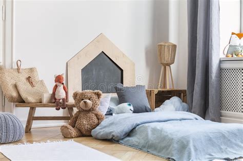 Teddy Bear Next To A Bed Covered With Blue Sheets In A Natural Kid Room