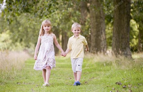 Dos Niños Pequeños Caminando Por El Camino Tomados De La Mano Sonriendo