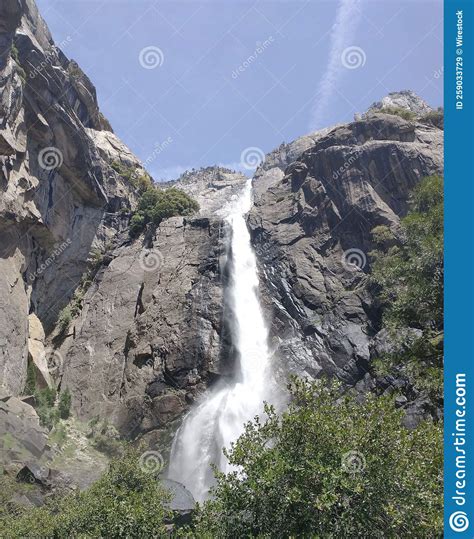 Vertical Shot Of A Rocky Waterfall With Splashing Water On A Bright
