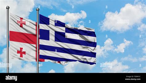 Georgia And Greece Flag Waving In The Wind Against White Cloudy Blue