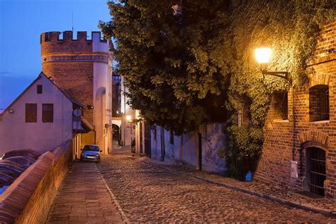 Podmurna Street And Bridge Tower By Night In Torun Photograph By Artur