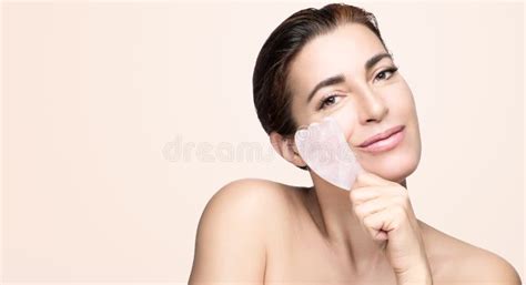 Beauty And Skincare Concept With A Beautiful Woman Doing Skin Care Routine With Gua Sha Tool