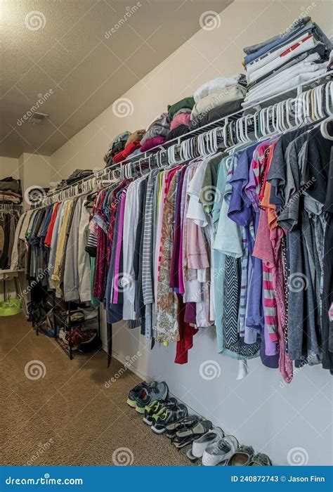 Vertical Walk In Closet With Organized Hanging And Stacked Clothes And