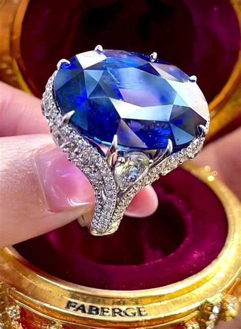 Someone Is Holding A Fancy Ring With A Blue Stone In It S Center And