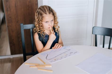 Thoughtful Preschool Girl Coloring Picture At The Table Stock Photo