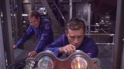 Two Men In Space Suits Looking At Something