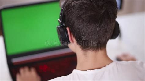 Back View Of Young Boy Play Game On Laptop Green Screen In Laptop