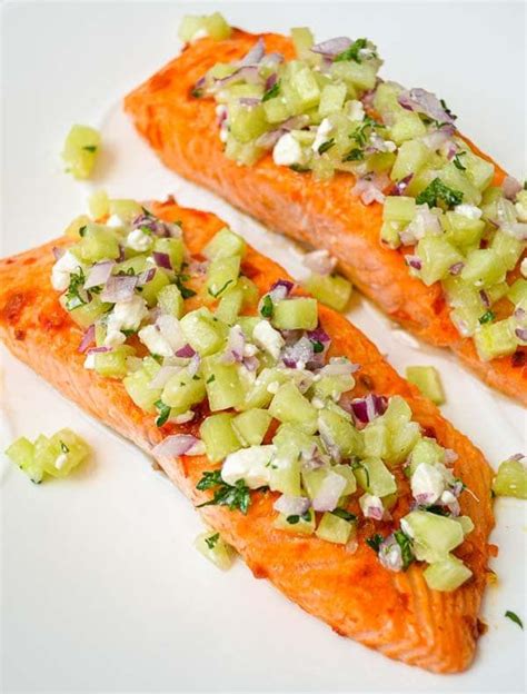 Two Salmon Fillets With Onions And Celery Garnish On A White Plate