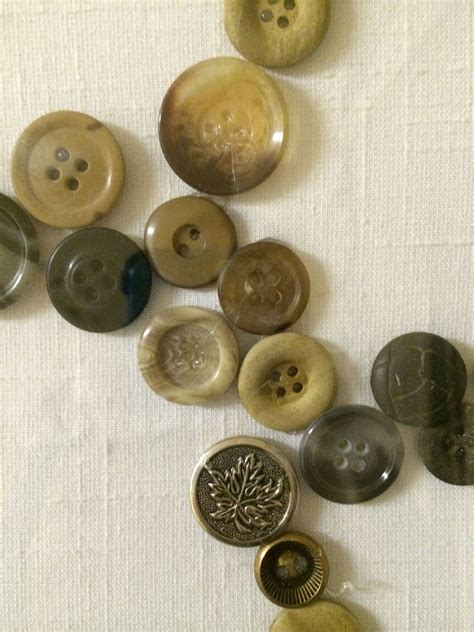 Several Different Types Of Buttons On A White Table Cloth With One