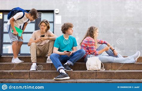 Teens With Smartphones On Stairs Beside Shool Building Stock Photo