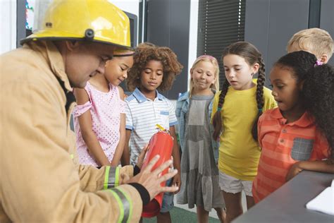 Firefighter Teaching About Fire Extinguisher To School Kids In