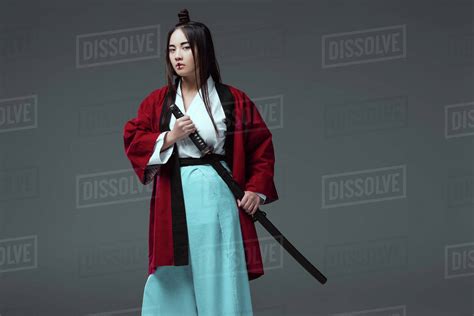 Young Asian Woman In Kimono Holding Katana Sword And Looking At Camera