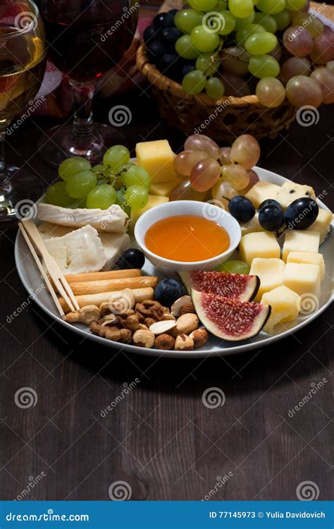 Plate Of Cheeses Snacks Fruits And Wine On A Dark Background Stock