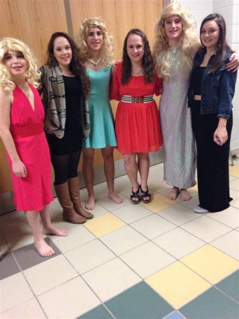 four women are posing for the camera in front of a bathroom wall with tiled floors