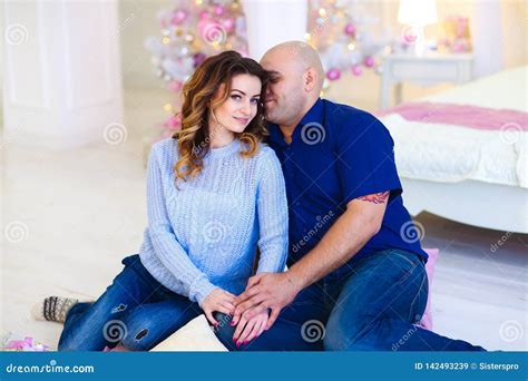 Happy Husband Hugging Wife And Sitting Near Decorated Christmas Tree