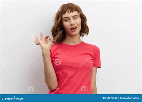 a happy joyful woman poses standing on a white background in a pink t shirt and smiling
