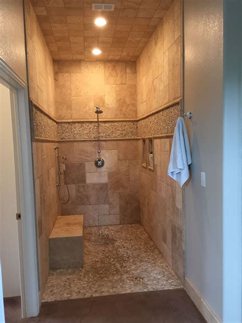 When we refer to a shower door we're basically talking about the entry hardware to a shower space. Walk in shower, no door, travertine and pebble tile ...