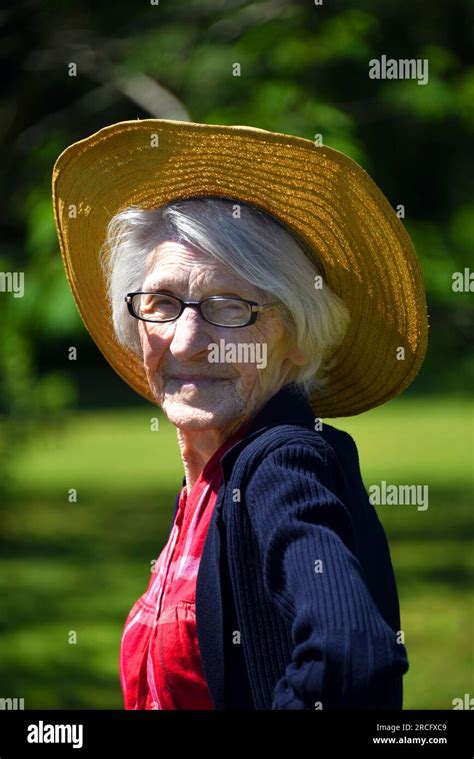 One Hundred Year Old Country Woman Stands Outdoors In Her Red Plaid Shirt And Straw Hat The Sun