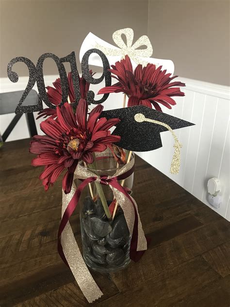 a vase filled with red flowers on top of a wooden table next to a sign