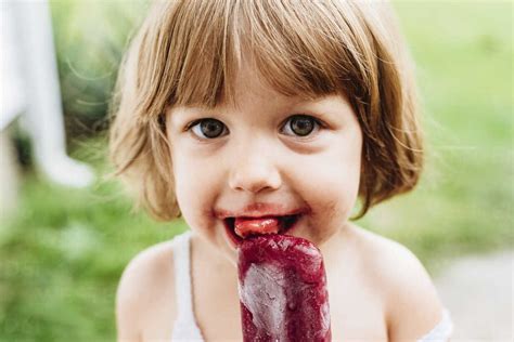Close Up Portrait Of Girl Eating Popsicle Stock Photo