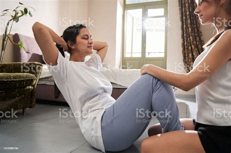 Woman Helping To Her Bestie Pump Press While Holding Her Legs Stock