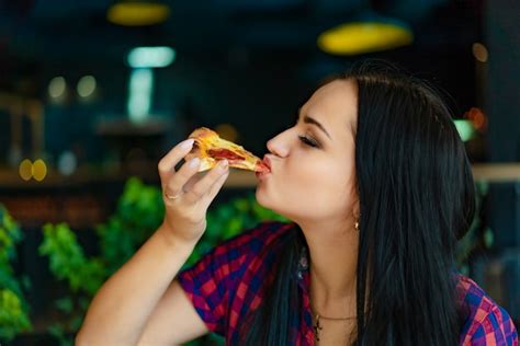 premium photo beautiful brunette girl in t shirt eating pizza at restaurant a pretty girl