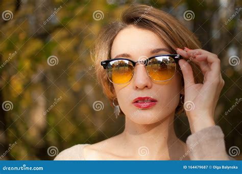 Young And Beautiful Girl With Short Hair And Yellow Sunglasses With Mirror Surface Is Posing