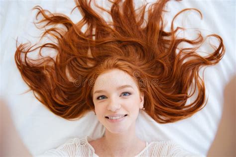 Smiling Woman With Long Red Hair Taking Selfie In Bed Stock Photo