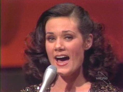 A Woman Singing Into A Microphone While Wearing A Sequined Top And